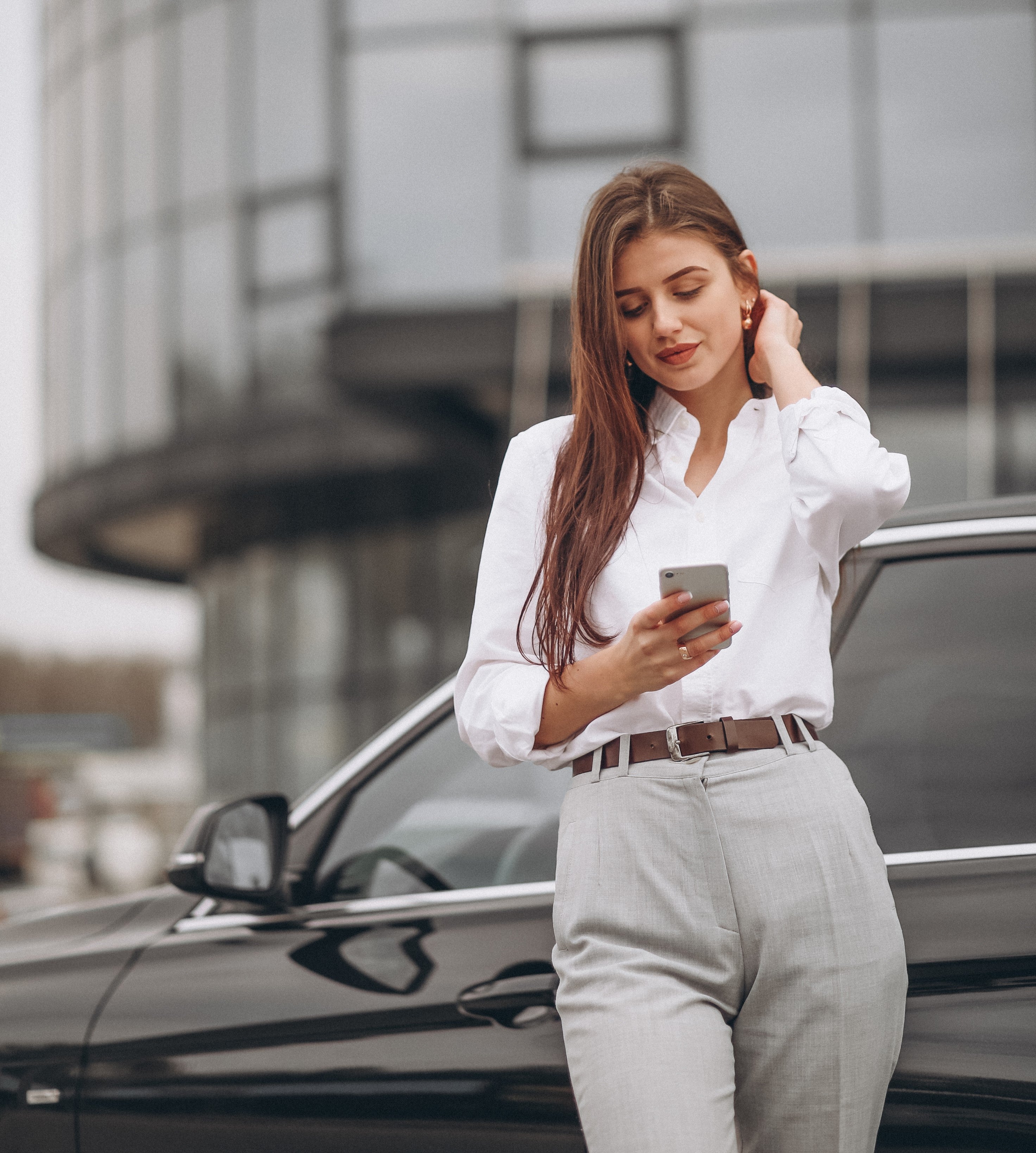 business-woman-standing-by-car-using-phone